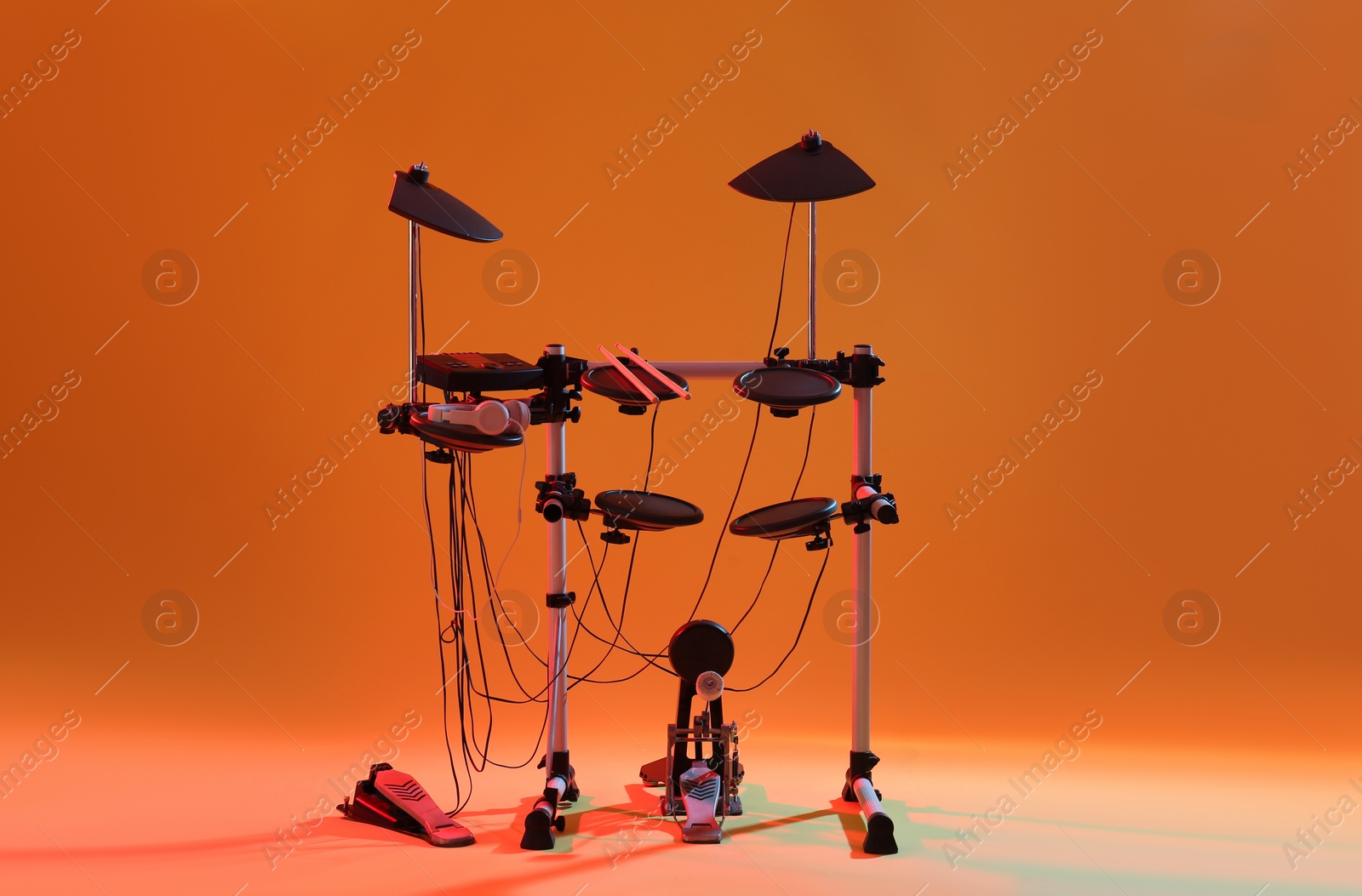 Photo of Modern electronic drum kit on orange background. Musical instrument