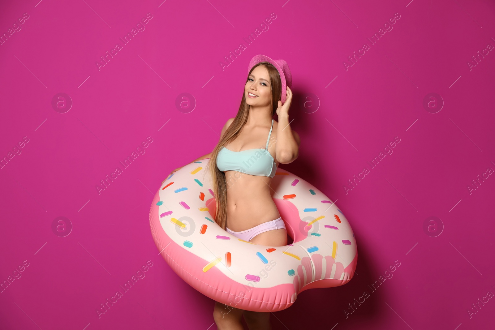 Photo of Beautiful young woman in bikini with inflatable ring against color background