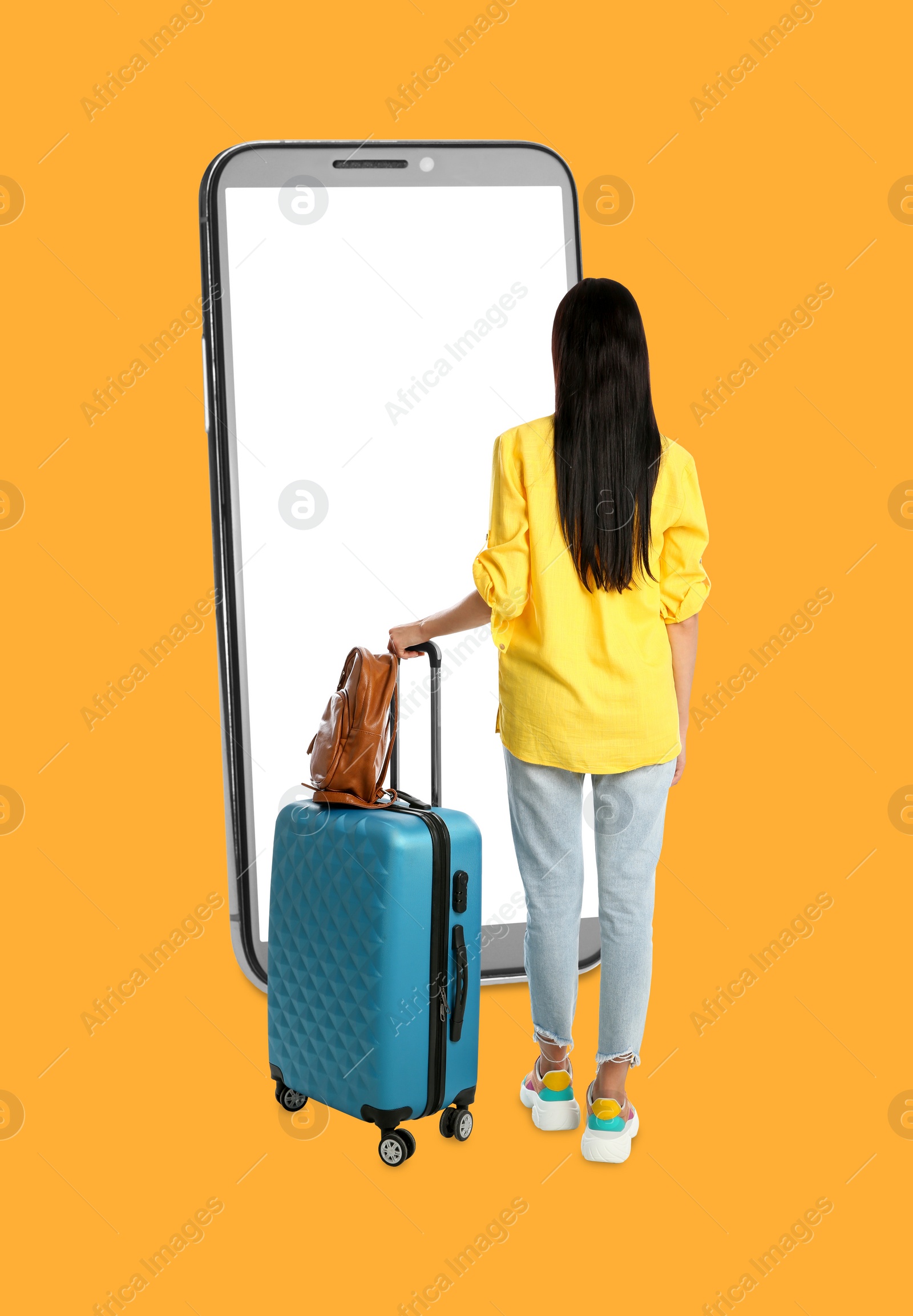 Image of Traveler with suitcase standing in front of big smartphone on orange background