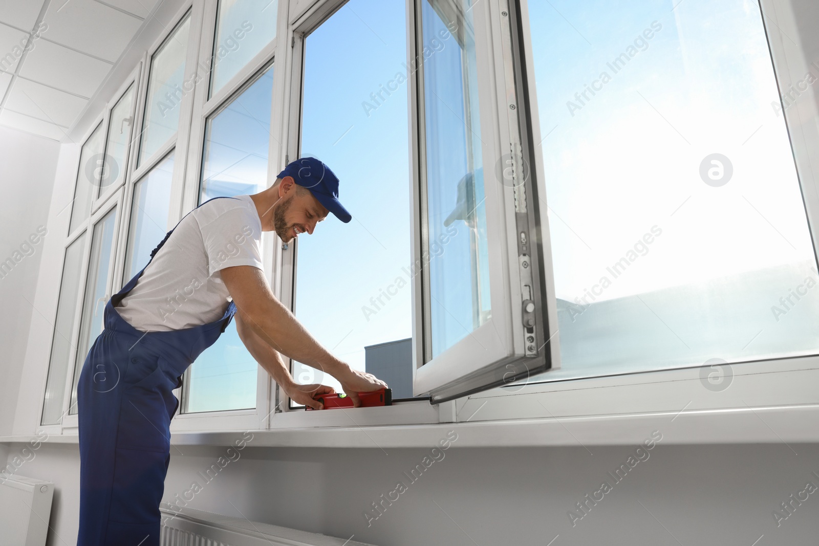 Photo of Worker using bubble level after plastic window installation indoors