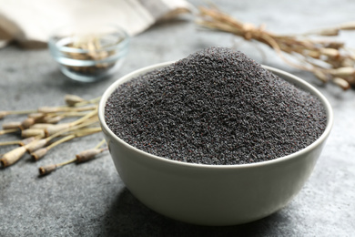 Photo of Poppy seeds in bowl on grey table