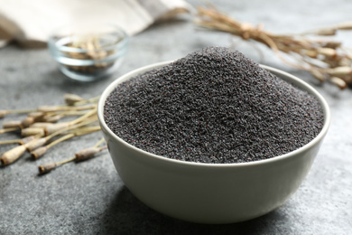 Poppy seeds in bowl on grey table