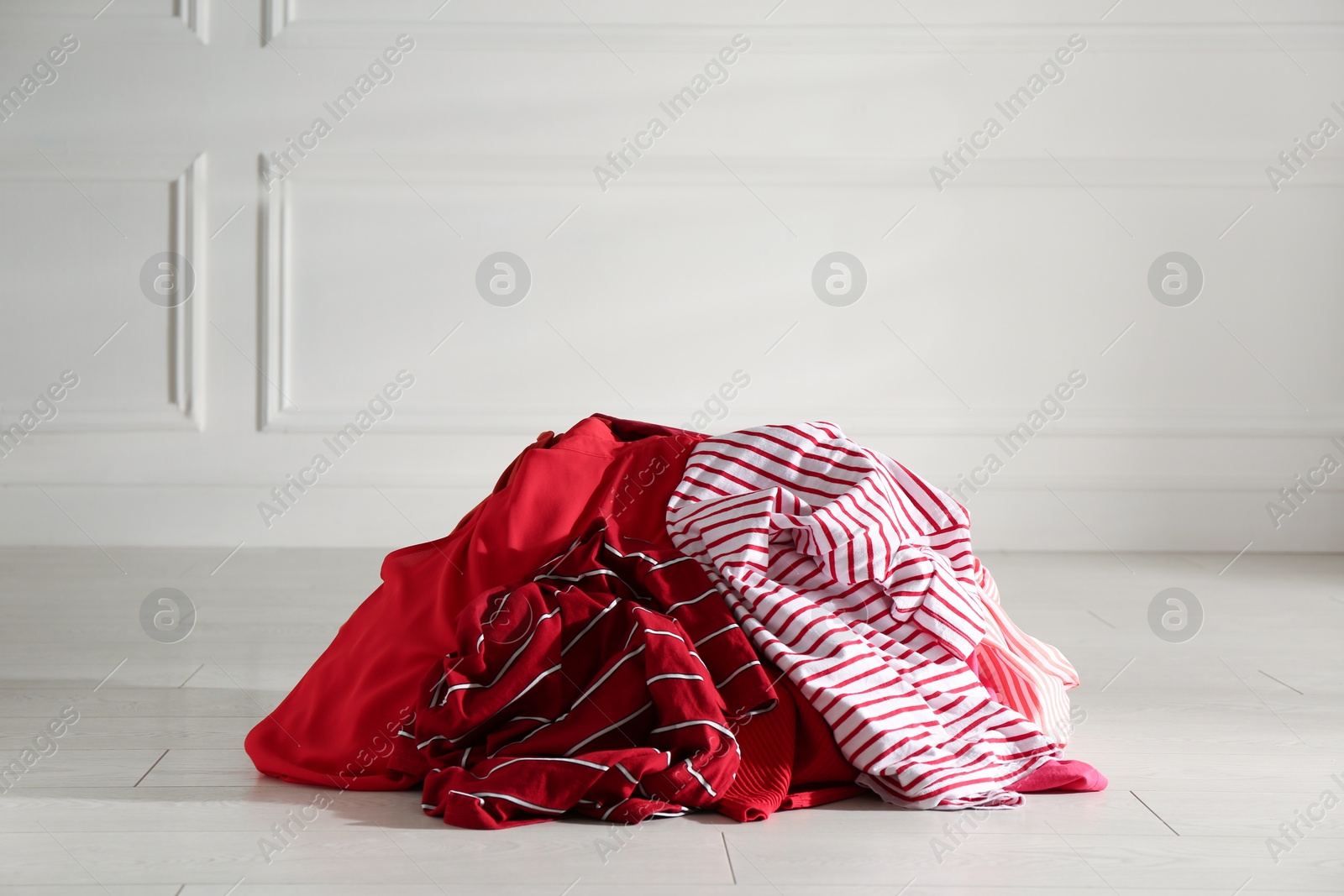 Photo of Pile of dirty clothes on floor near light wall indoors