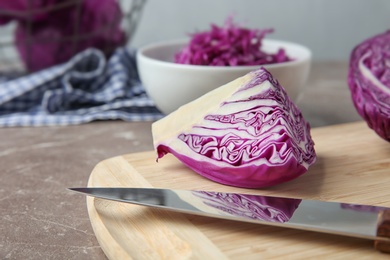 Photo of Fresh red cabbage, knife and cutting board on kitchen table