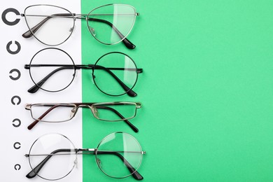Photo of Vision test chart and glasses on green background, flat lay. Space for text