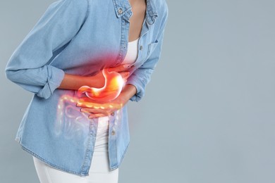 Image of Woman suffering from stomach ache on grey background, closeup with space for text. Illustration of unhealthy gastrointestinal tract