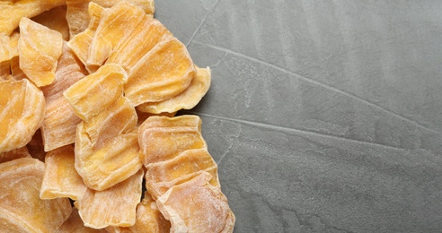 Photo of Delicious dried jackfruit slices on grey table, flat lay. Space for text