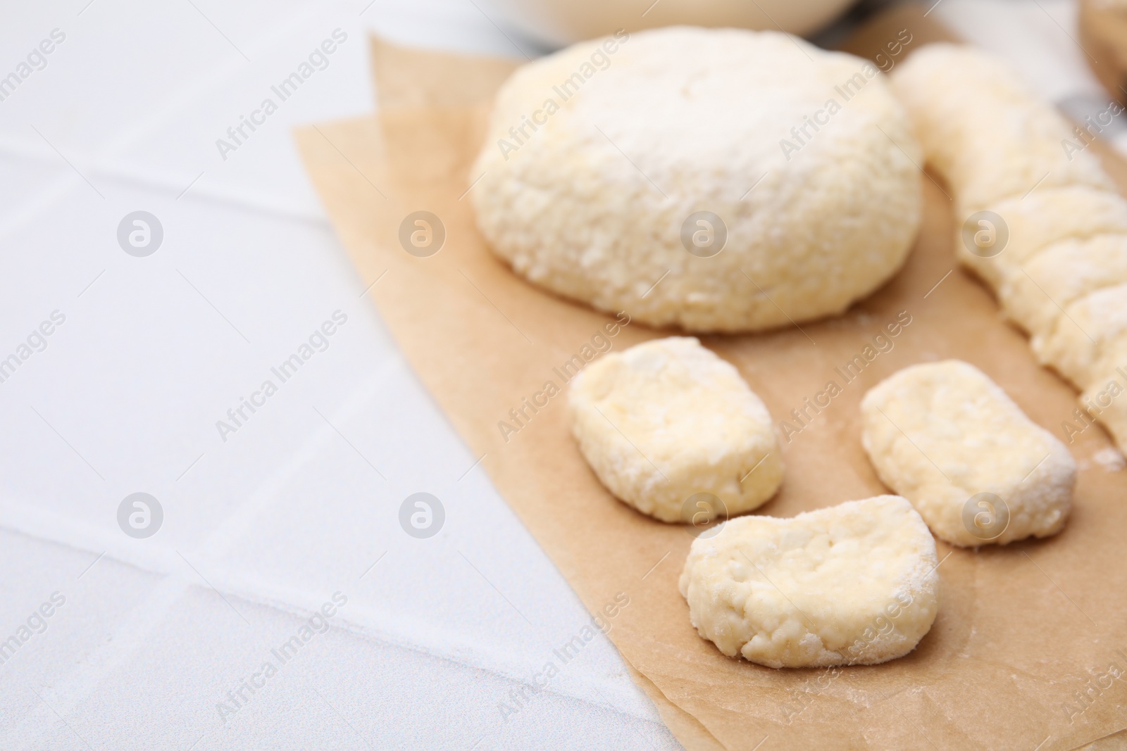 Photo of Making lazy dumplings. Raw dough on white tiled table, closeup. Space for text