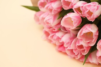 Photo of Beautiful bouquet of fresh pink tulips on beige background, closeup. Space for text