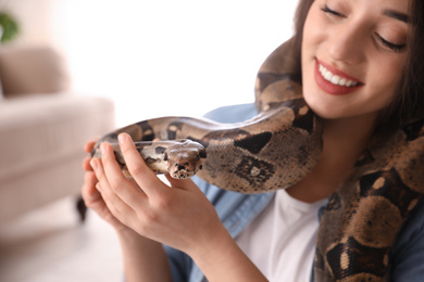 Young woman with her boa constrictor at home, focus on hand