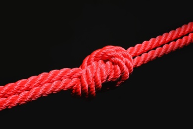 Photo of Red rope with knot on black background