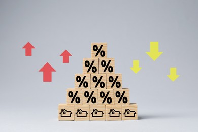 Image of Mortgage rate swings illustrated by percent signs, upward and downward arrows. Wooden cubes with house icons on gray background