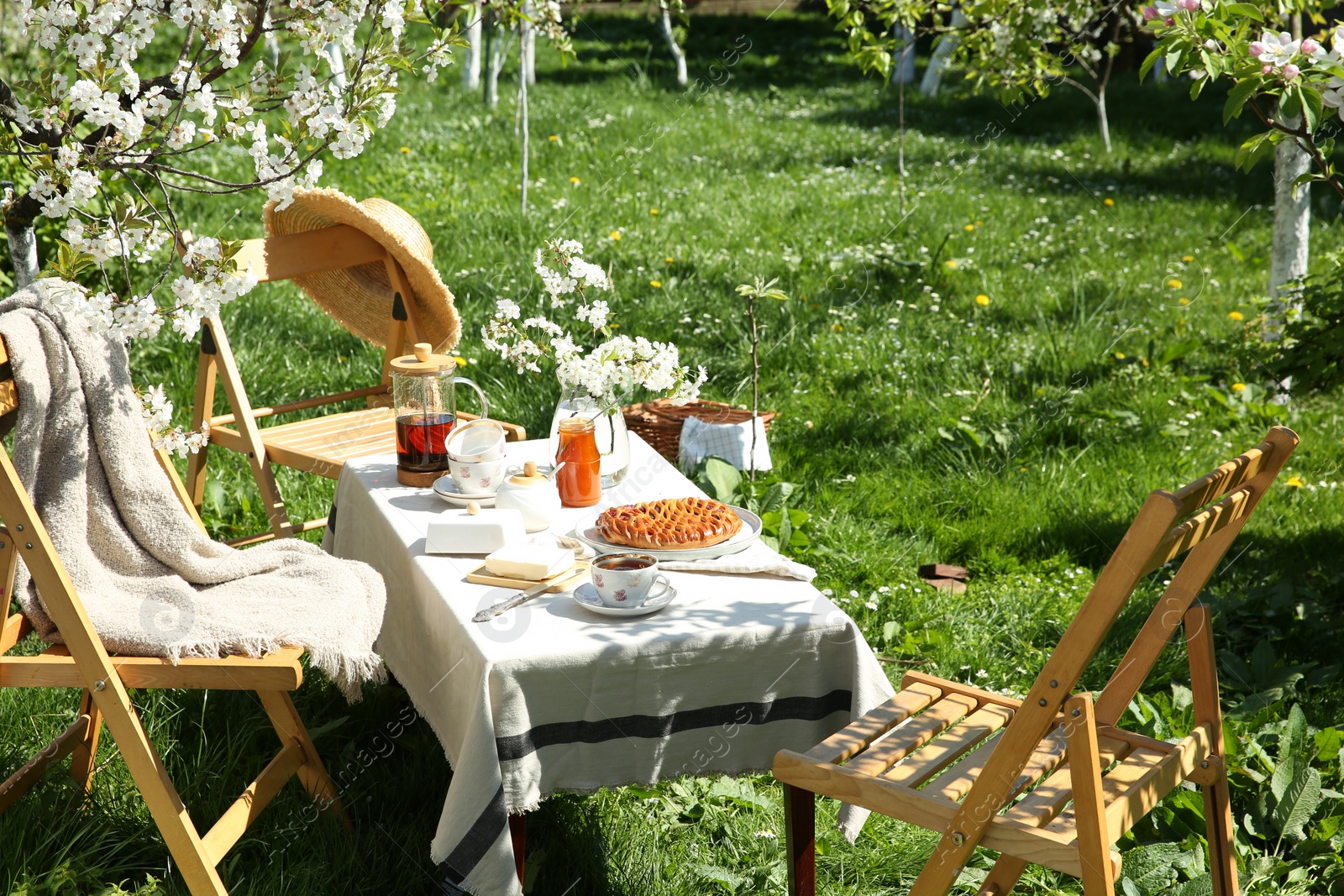 Photo of Beautiful table setting with spring flowers in garden on sunny day