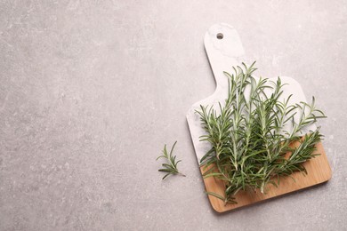 Photo of Sprigs of fresh rosemary on light grey table, top view. Space for text