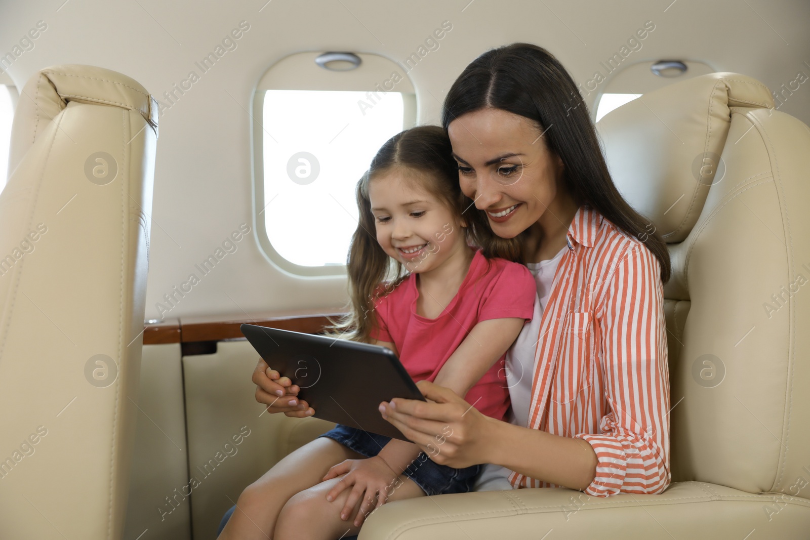 Photo of Mother with daughter using tablet in airplane during flight