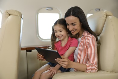Photo of Mother with daughter using tablet in airplane during flight