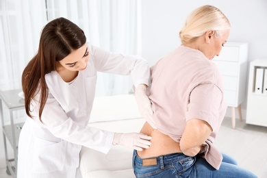 Dermatologist examining mature patient's birthmark in clinic