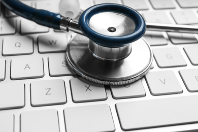 Photo of Stethoscope on keyboard, closeup. Concept of technical support
