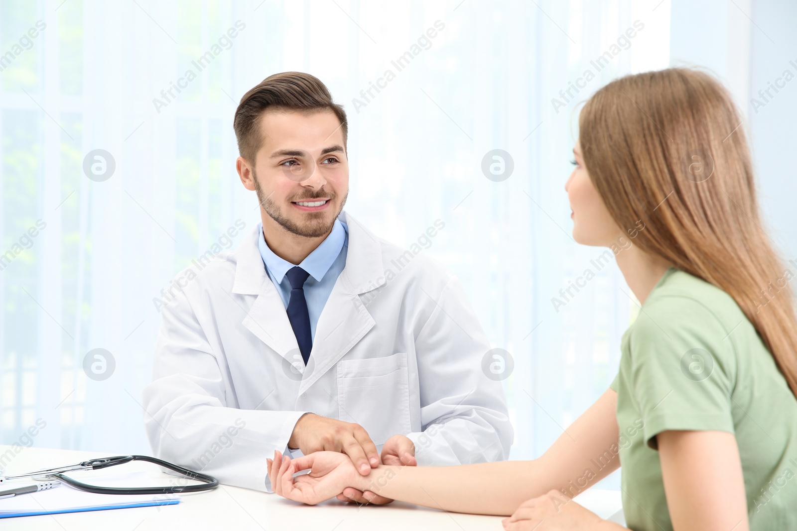 Photo of Doctor checking young woman's pulse in hospital