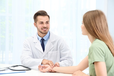 Doctor checking young woman's pulse in hospital