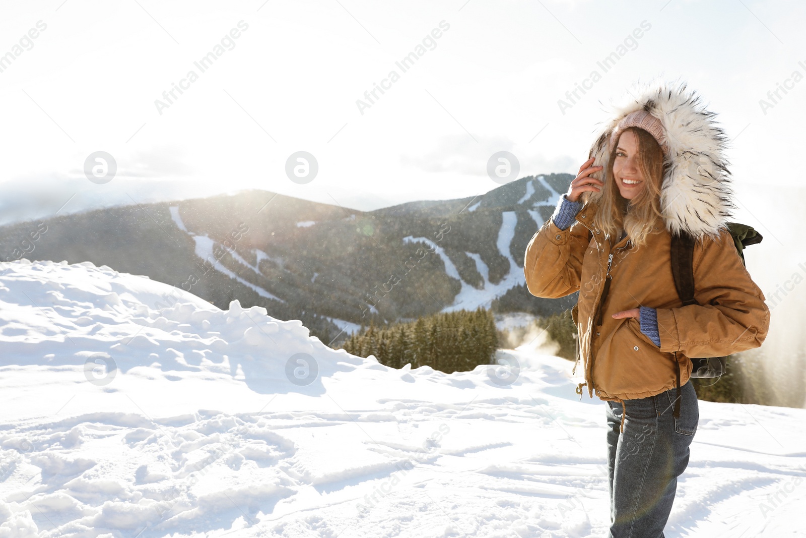 Photo of Happy young woman with backpack spending winter vacation in mountains. Space for text