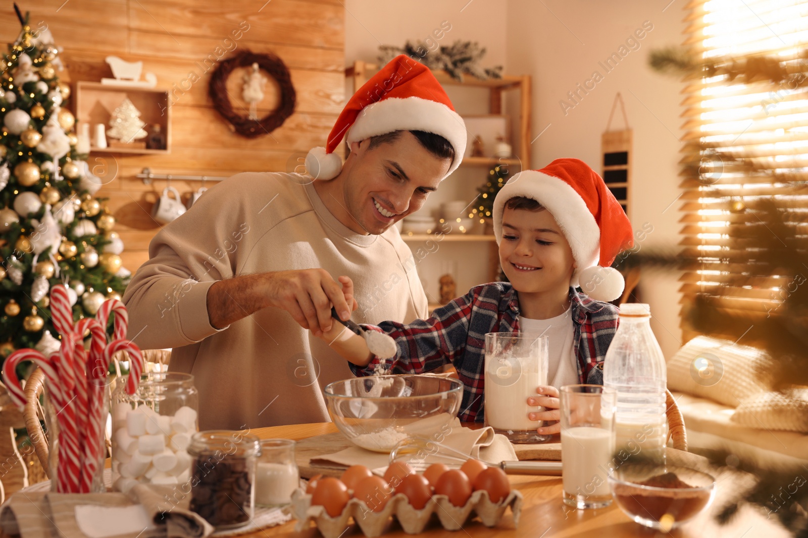 Photo of Happy father and his son making dough for Christmas cookies at home