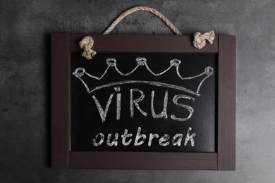 Blackboard with words Virus Outbreak on grey table, top view