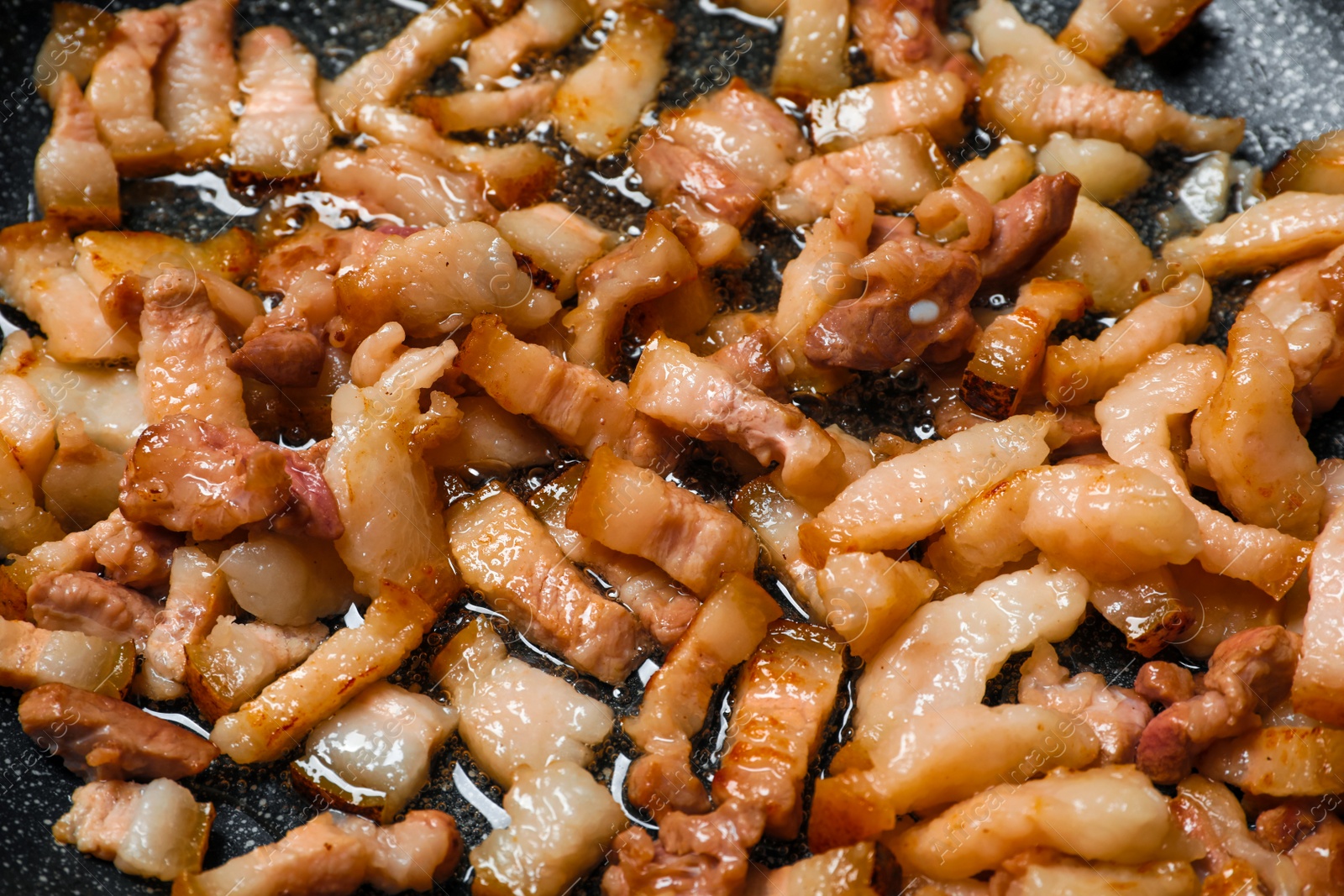 Photo of Frying cracklings in cookware, closeup. Pork lard