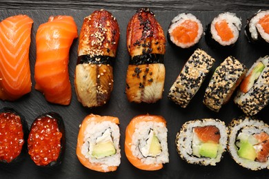 Photo of Set of delicious sushi rolls on black wooden table, top view
