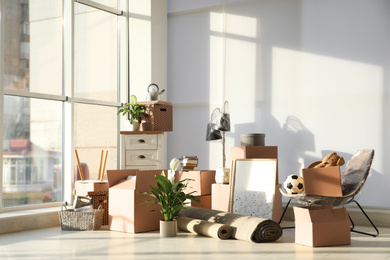 Photo of Cardboard boxes and household stuff in living room. Moving day