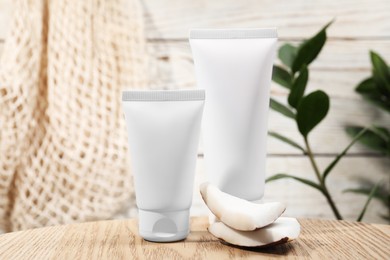 Tubes of hand cream and coconut pieces on wooden table