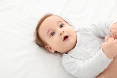 Photo of Portrait of adorable baby lying on bed. Space for text