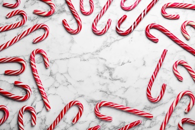 Photo of Sweet Christmas candy canes on white marble background, flat lay. Space for text