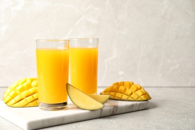 Photo of Fresh mango drink and cut fruits on table. Space for text