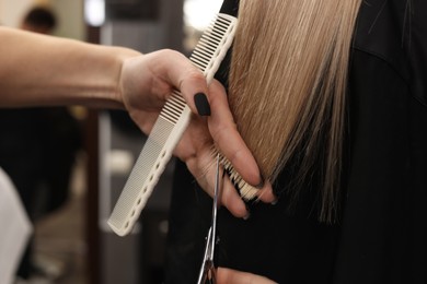 Professional hairdresser cutting woman's hair in salon, closeup