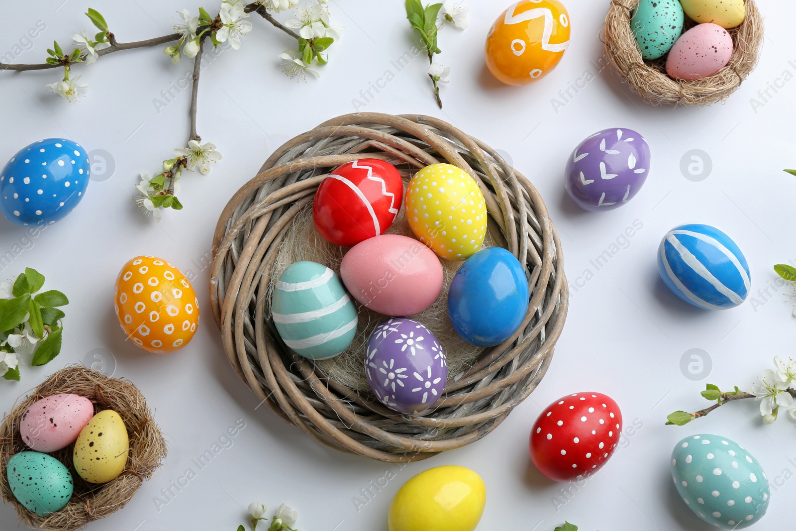 Photo of Flat lay composition with painted Easter eggs and blossoming branches on white background