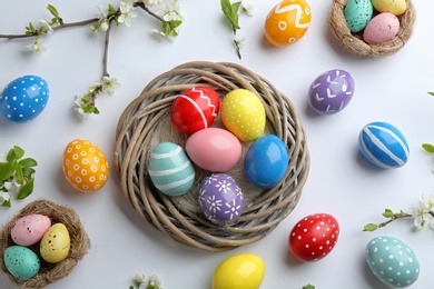 Photo of Flat lay composition with painted Easter eggs and blossoming branches on white background