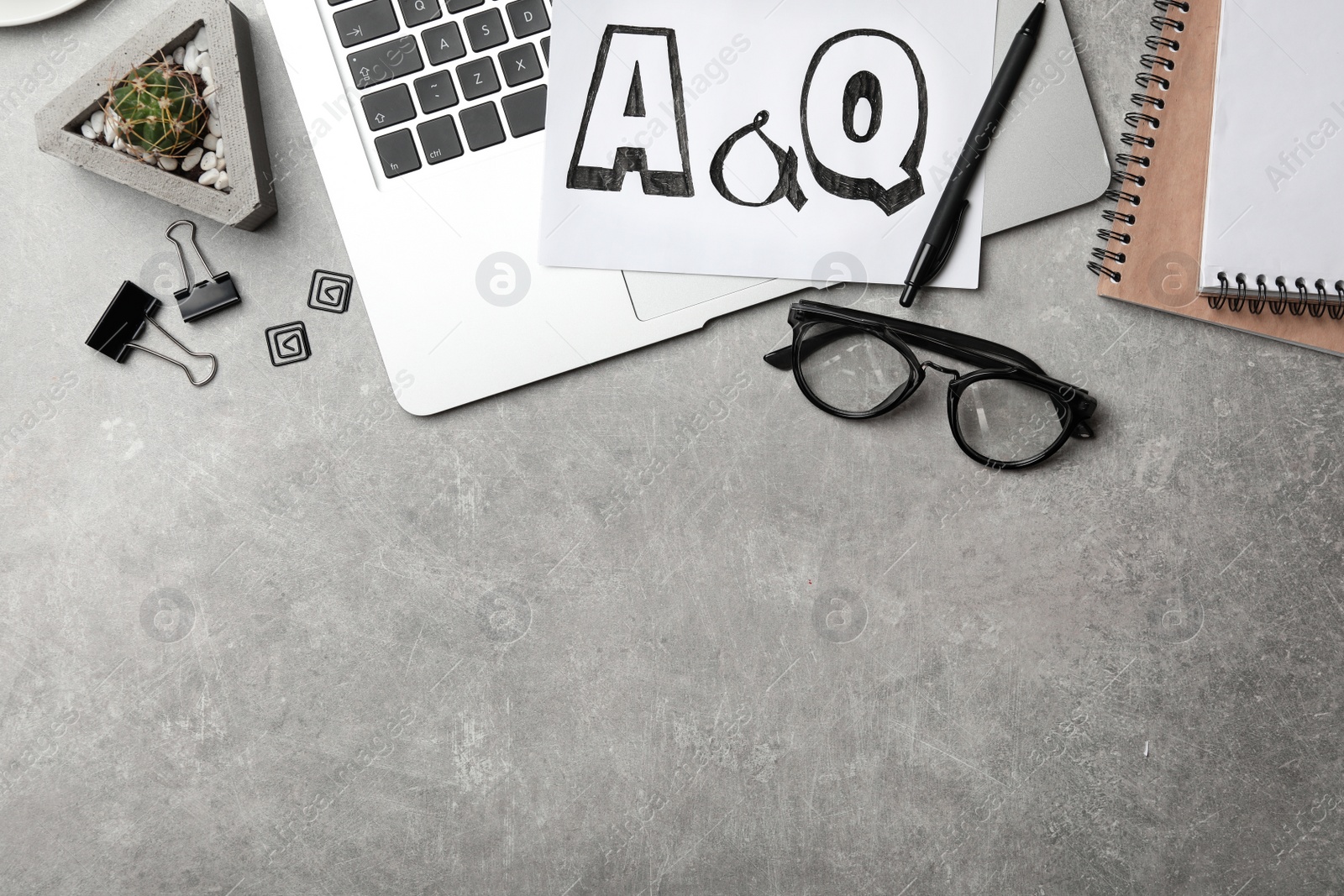 Photo of Notebook with phrase A&Q and laptop on grey table, flat lay. Space for text