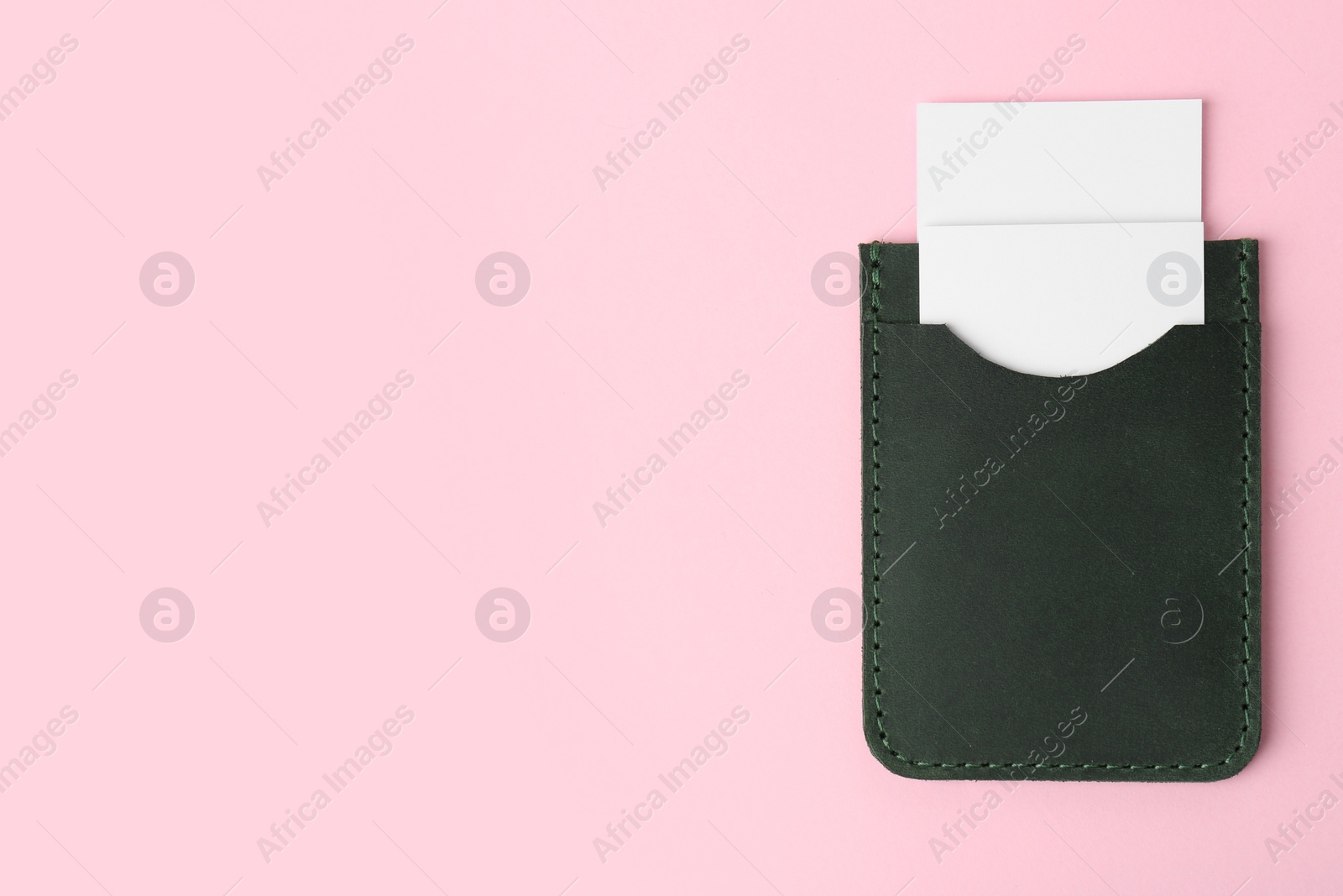 Photo of Leather business card holder with blank cards on pink background, top view. Space for text