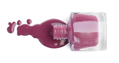 Photo of Overturned bottle of violet nail polish isolated on white, top view