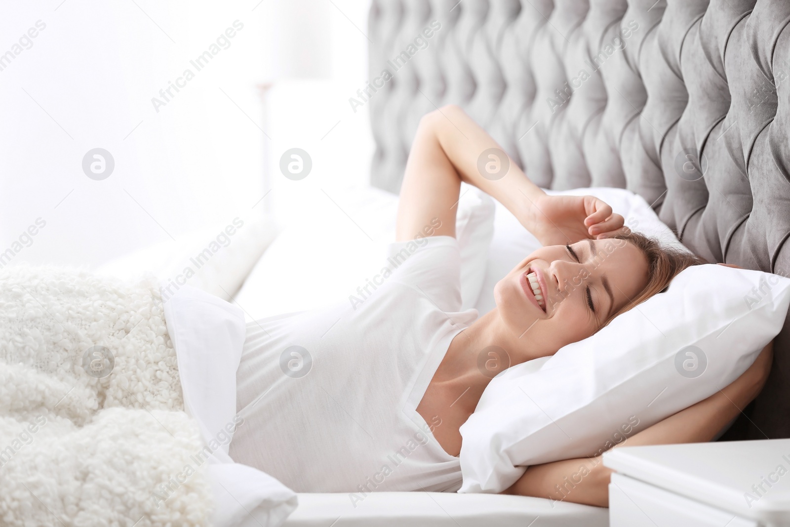 Photo of Young beautiful woman waking up after sleeping in bed at home
