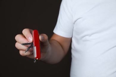 Photo of Man holding multitool on dark background, closeup