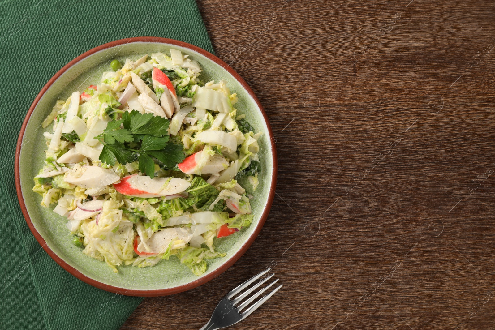 Photo of Delicious salad with Chinese cabbage, crab sticks and parsley on wooden table, top view. Space for text