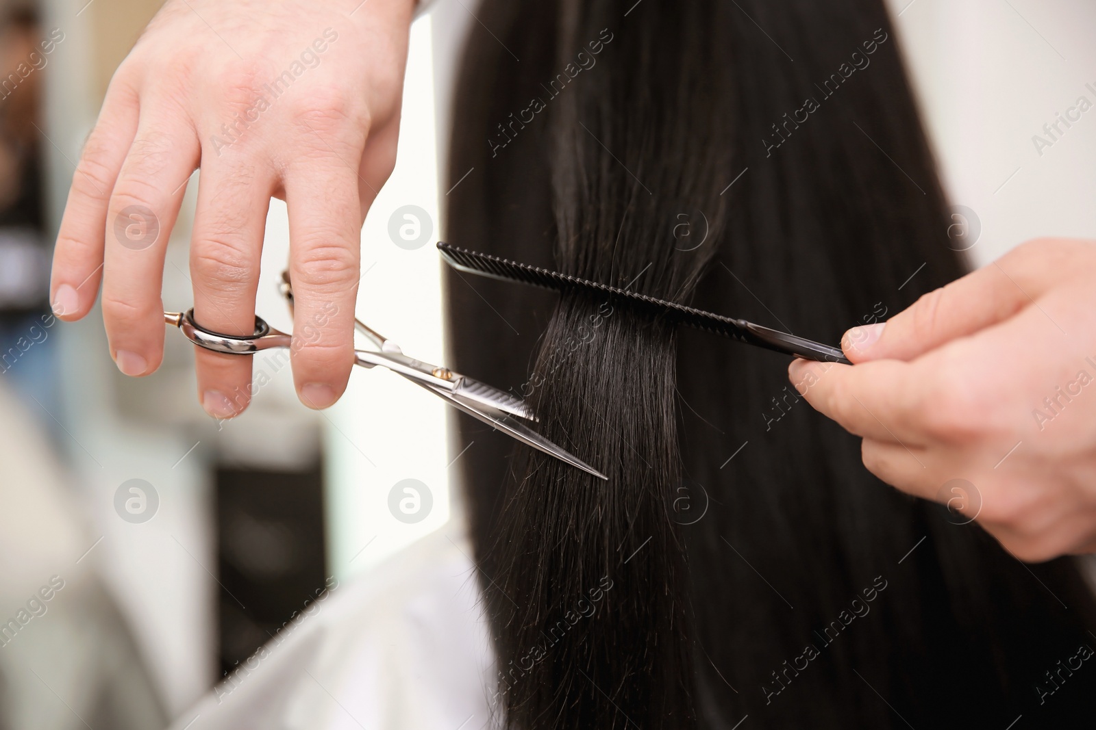 Photo of Professional male hairdresser working with client in salon