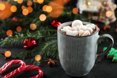 Photo of Delicious hot chocolate with marshmallows and Christmas decor on black table, closeup. Space for text