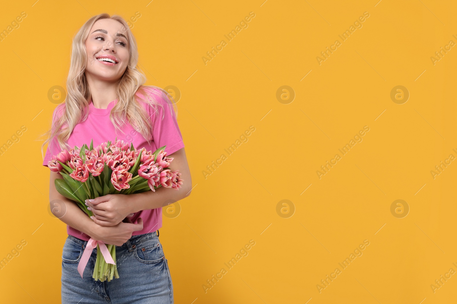 Photo of Happy young woman with beautiful bouquet on orange background. Space for text