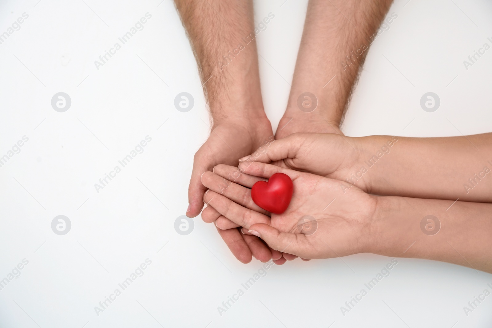 Photo of Young couple with red heart on white background, top view