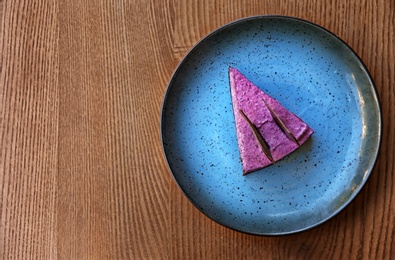 Plate with slice of berry cheesecake on wooden table, top view. Space for text