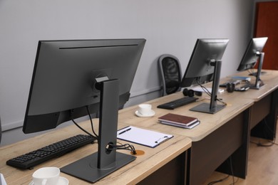 Photo of Open office interior. Modern workplaces with computers near light grey wall