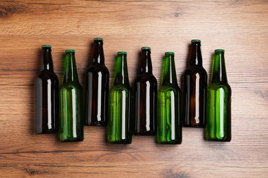 Bottles of tasty beer on wooden table, flat lay